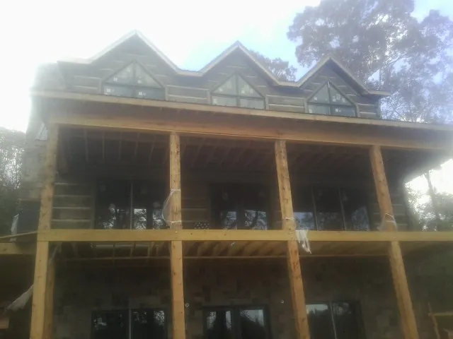 Dormers and porch framing on a large log home under construction — Roof Coating work by our crew in Veteran