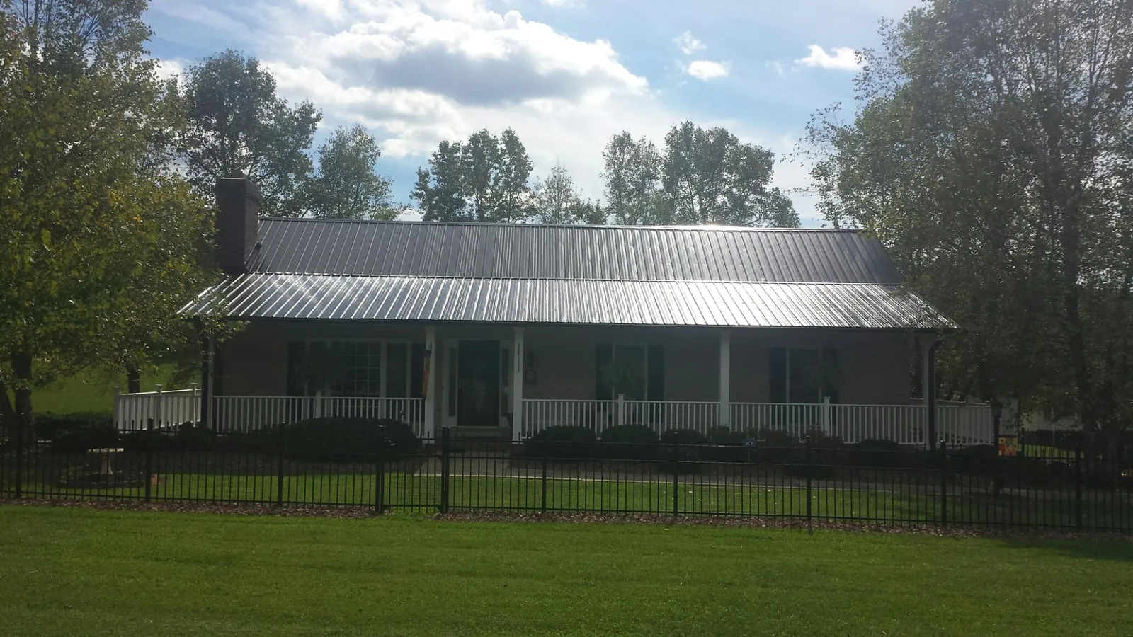 Gray metal roof on a brick ranch with a full width front porch — Gutter Guard Installation work by our crew in Veteran