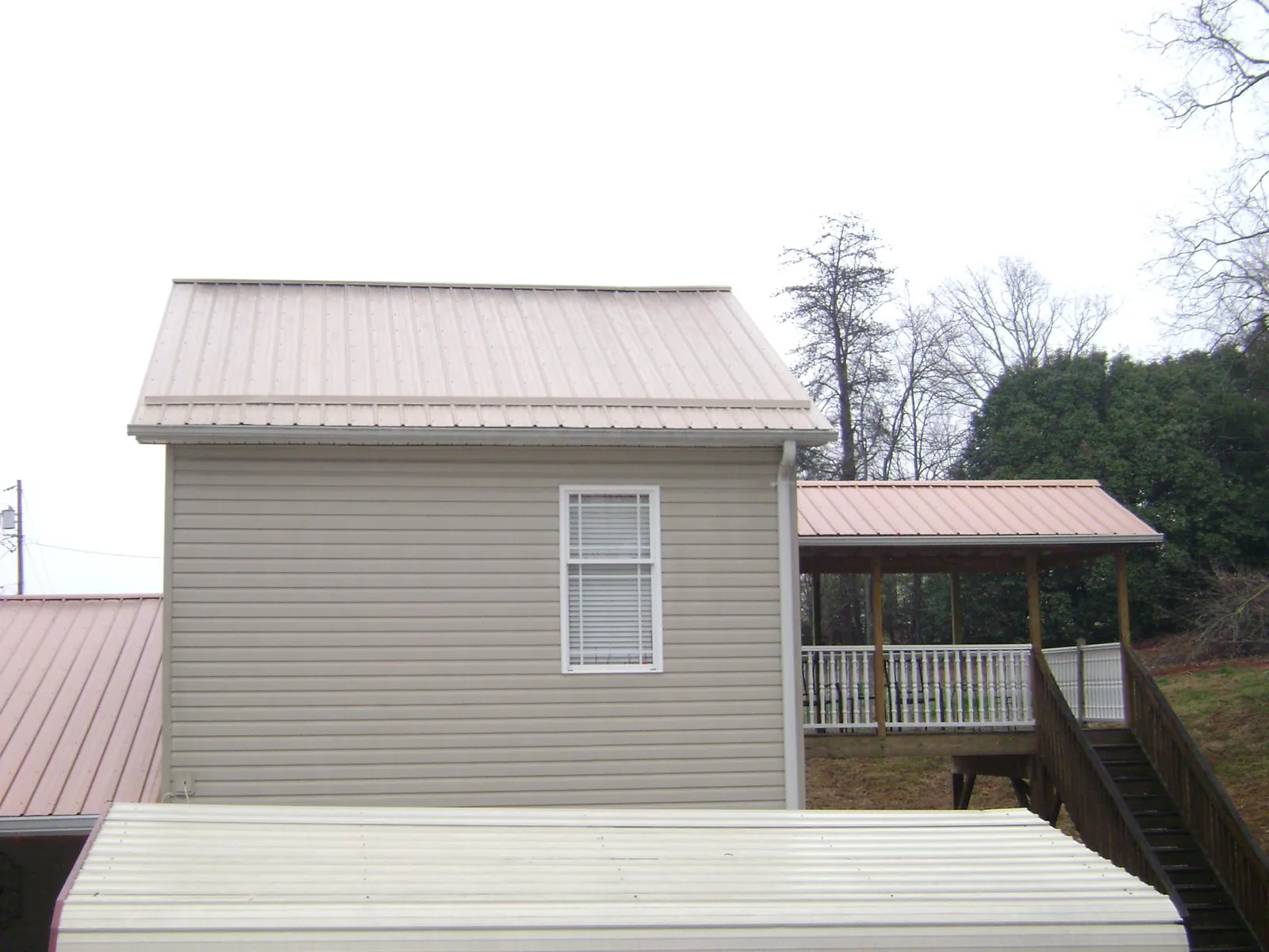Tan metal roofs on a two story addition and attached porch, from a Roof Replacement job in Veteran